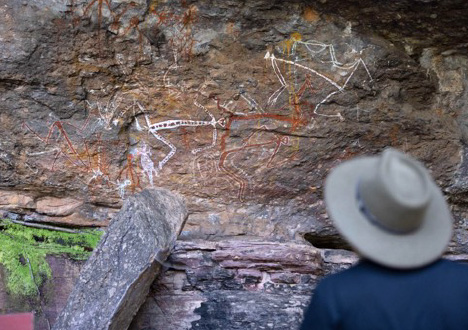 Tourist viewing aboriginal drawings on a rock formation.