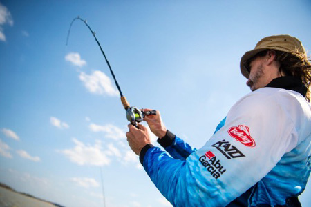 A close-up of an angler and his fishing pole in the midst of catching a fish.