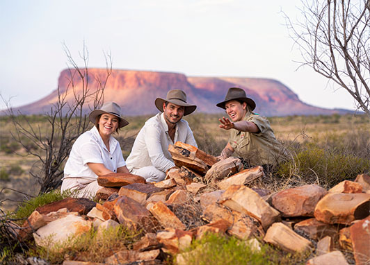 A couple listens to a park ranger with Uluru in the background.