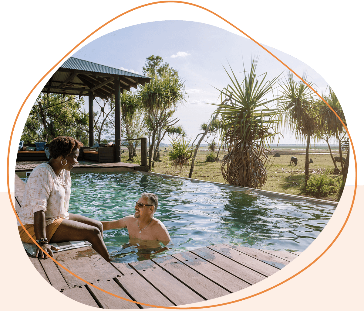 A couple enjoys a swimming pool at an outdoor veranda.