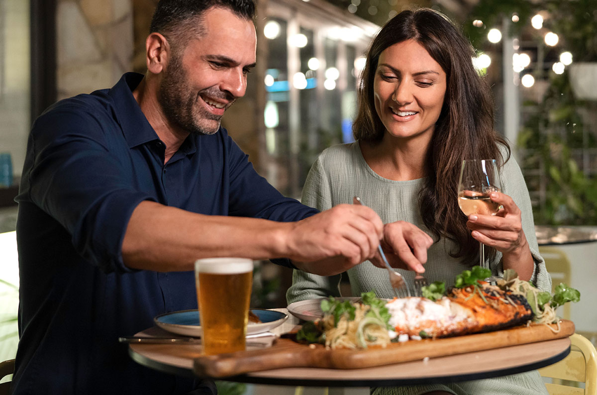 A couple enjoys dinner and drinks at a restaurant.