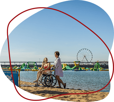 Two women, one in a wheelchair, enjoy a beach.