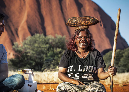 An Aboriginal woman balances wood artwork at the Maruku Arts Gallery.