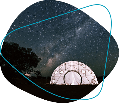 A domed tent lit from inside undera clear, starry sky