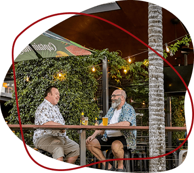 Two friends share a beer at an outdoor bar.